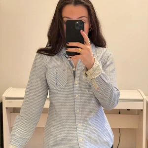 Skjorta Tommy Hilfiger XS - Blå rutig skjorta från Tommy Hilfiger. Väldigt söta blommdetaljer. Storlek XS.
