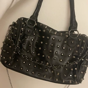 Cool väska med nitar  - OBS! SÅLD för direktpris!!! Säljer denna coola väska med nitar som är helt oanvänd! Så snygg! Inget speciellt märke. Säljer till högstbudande, buda (privat) bara om du kan och vill köpa den ❤️❤️ jag skickar gärna fler bilder!! OBS!!!!!! DET LÅNGA SILVRIGA KEDJEBANDET MEDFÖLJER INTE, men det långa svarta avtagbara bandet på bild 2 medföljer!! Det korta bandet (silversvarta) som hänger på framsidan är avtagbart! Köpt för 500-600