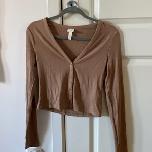 Beige tröja  - Långärmad T-shirt med knappar på magen från HM. Använd en gång och säljer pga för stor vid bysten. Nypris 199💛