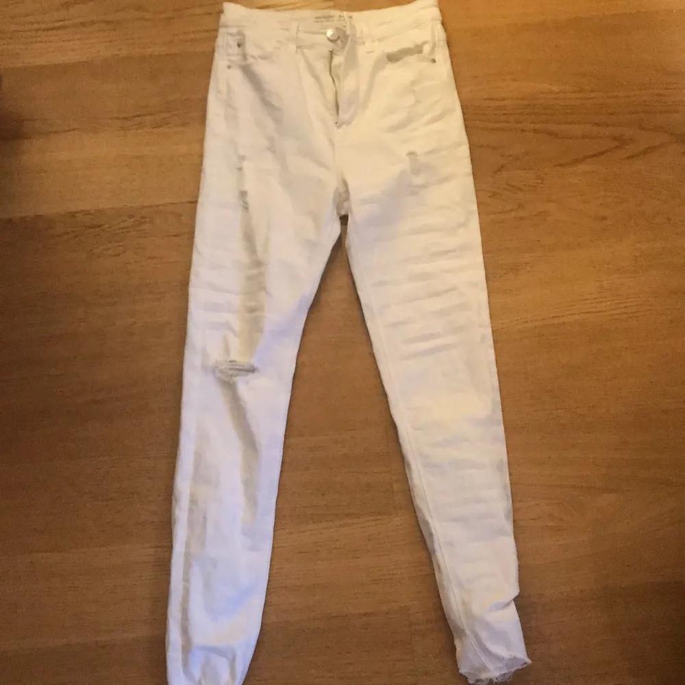 Ett par vita jeans med hål vid ett knä och vid fickorna. Jeansen är använda ett få tal gånger och är i ett bra skick. Lite oklart vart de är ifrån men de är i storlek 36. De är högmidjade. De kostar 150+ 30 kr i frakt. Jeans & Byxor.