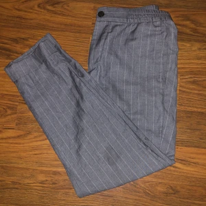 Grå kostymbyxor pinstriped  - Säljer ett par grå pinstriped kostymbyxor i tunt mjukt material. Supersnygga och sköna, mycket använda men i bra skick utan slitningar. 44 herrstorlek men sitter bra på S/M och är unisex. Har dessutom resår i midjan så de sitter bra, straight fit