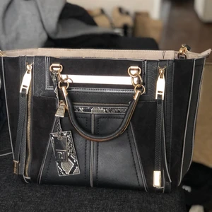 Rymlig väska från River Island - Stor handväska som rymmer det mesta. Har ett långt band att fästa så man kan hänga den över axeln. 👜 Väskan är flitigt använd men i ok skick, därav priset. Den har några fläckar inuti, och veck av att den legat i en låda länge. Pris kan diskuteras! 🌸