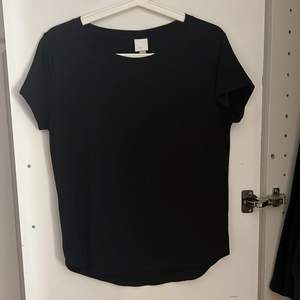 En svart T-shirt från H&M i storlek S, lite längre bak, använd fåtal gånger