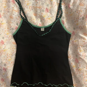 Svart linne med gröna detaljer  - Så fint v-ringat svart mesh linne med grön detalj uppe och nere. Köpt på plick men använder tyvärr aldrig. Fint skick, pyttelite genomskinlig men funkar ändå att ha utan bh tycker jag. Kan mötas i Stockholm annars betalar köpare frakt. 