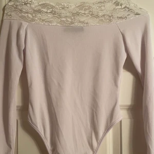 Vit spets off shoulder bodysuit - En vit spets off shoulder som är en body. Denna är helt OANVÄND och i väldigt bra skick. Den är i storlek 36 och är väldigt snygg på den sitter tajt och formar kroppen snyggt. Den passar även dig som har 34,36,38. Då den har stretch och formar sig efter din kropp. Toppen har snygg spets detalj och är i ribbat material. Passar alla tjejer där ute i alla former💓