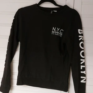 Svart sweatshirt  - Svart sweatshirt med vit text både fram och på ärmarna 