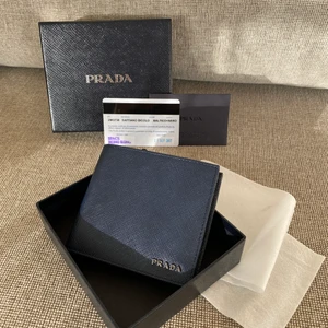 Prada Saffiano Leather Wallet  - Saffiano plånbok i skinn från Prada. Denna är oanvänd då tanken var att min pappa skulle få den i födelsedagspresent. Finns nu ute online för 4560:-. Mitt pris: 3560:- prutat och klart. Färgen är i Pradas klassiska box, Dark navy blue samt svart (se bilder).