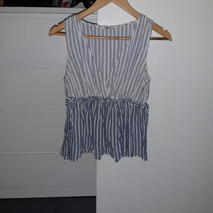 Blus - En blå/vit blus perfekt till sommaren. Den e linne aktig o har typ små volanger precis under brösten funkar med och utan bh.