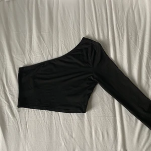 One shoulder topp - Säljer denna ursnygga one shoulder topp som använts ett fåtal gånger. En defekt är att det varit ett litet hål upp till sömmarna på ryggen men det är fixat då jag sytt ihop det! Vet ej vart den kommer ifrån då jag fått den av en vän! Frakt är ej med i priset!🤍 gör av er vid mer bilder!