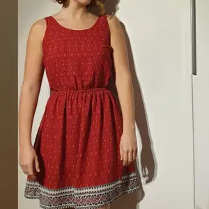 Röd mönstrad klänning med öppen rygg (fluga) 80 cm lång. Polyester.