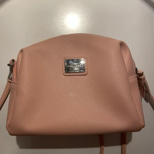 Rosa handväska - Rosa handväska med dragkedja och ett smalt band! Köpt för ungefär 400kr men de var ett tag sen! Har en liten fläck men har aldrig stört mig på den, jättebra med två olika fickor i väskan och dragkedja på ena fickan! Säljer för 50+52kr frakt! 