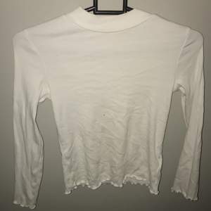 En vit långärmad tröja men lite volang/ vågig kant. Storlek 122-128. Men mycket större i storlek. 