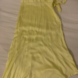 Silkeskjol - En citrongul silkeskjol från Other stories som är perfekt till sommaren. Den är snedskuren längst ner och har ett band i midjan. Den är använd ett ytterst få antal gånger och är som ny.