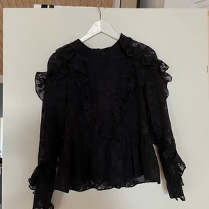 Blus - Mörkblå blus från H&M storlek 36, den är lite genomskinlig med blommigt mönster och volanger vid armar och i slutet av toppen.