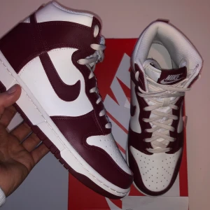 Dunk High Sail Team Red (W) - Säljer ett par höga dunks som passar perfekt inför våren. Dom är ett par stilrena skor och dom kommer i en vit vinröd färg. Dom har alldrig använd och kvitto box och allt med kommer. Jag möts i Stockholm och fraktar inom Sverige men köparen står för frakt.