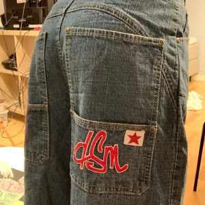 Alley Jeans Broderade Fickor - skitfräna vida/baggy jeans från alley med coola fickor !! kan användas både low o highwaist. midjan är 38cm liggandes, 31 cm mellan crotch och knapp, 54cm långa ben från innersömmen. jättebra skick, säljer då de är för korta för mig.skriv för fler bilder!