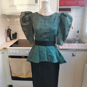Superfin vintageklänning tillverkad i Frankrike - One of a kind vintageklänning tillverkad i Frankrike. I fint skick med svarta pricka på skimrande grönt och en svart rosett vid ryggslutet. 70cm i omkrets runt midjan. 