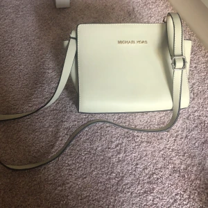 Michael kors väska - Säljer denna fina väskan för att den inte kommit till användning. Väldigt perfekt storlek för en liten handväska. Färgen är beige vilket nog inte helt kommer fram i bilderna. 