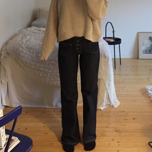 mörka bootcut jeans - Ett par bootcut jeans i mörkblått jeanstyg från Dr. Denim Jeansmakers. Fickorna är mindre än vad standard jeansfickor är. Jeansen har även istället för dragkedja som gylf, knappar hela vägen upp. Har medelhög midja. Byxorna är knappt använda och ser ut som nya. Strl 28/32 men skulle själv säga att dem sitter som 27/32.