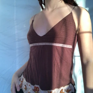 Brunt linne - Härligt brunt linne med fina glittriga detaljer. Visas på en 75A(s). Köpare står för 24kr frakt. Plagget är i gott second hand skick utan större defekter. Det finns ett litet hål längst ner på toppen men det är lätt att laga! 