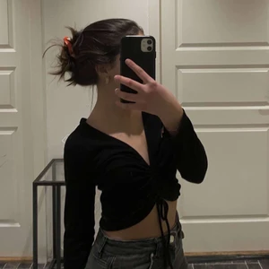 Svart topp - Modern och fin topp med knytning i mitten för en fin passform. Perfekt som festtopp eller till finare vardags! Plagget är i bra skick.