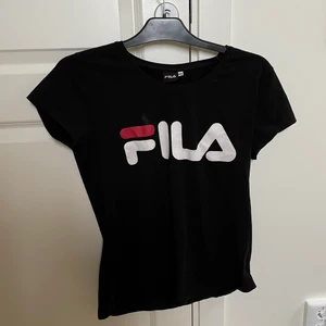 Fila T-shirt  - Stretchig svart fila T-shirt. Använd fåtal gånger. Storleken är 2XL men skulle påstå att den är mer en S/M