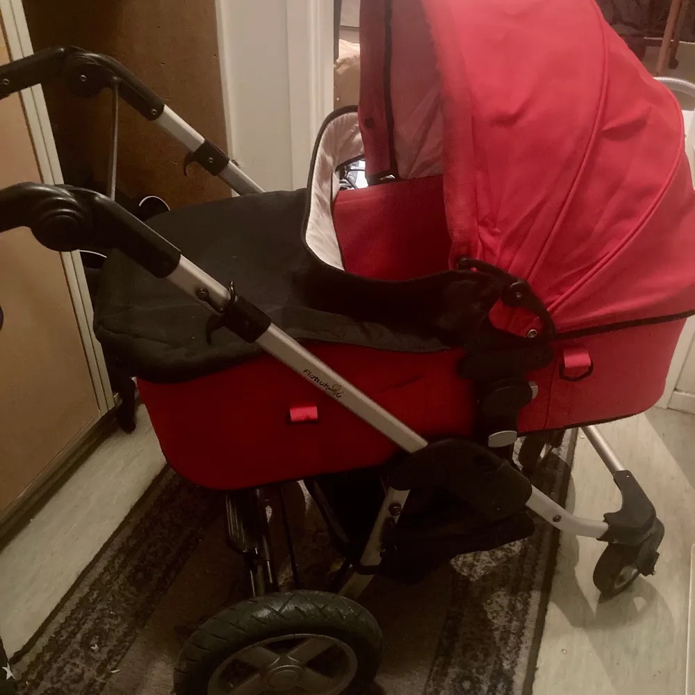 En röd barnvagn av märket first Wheel en amningskudde och ett babynest till salu paketpris. Övrigt.
