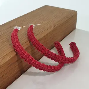 Örhänget är flätat i en platt röd lädertråd