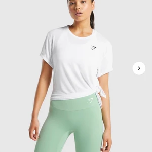 Gymshark tshirt - Träningstshirt från gymshark med knyten. Man kan knyta olika hårt och därmed avgöra hur högt upp den ska sitta. Knappt använd. Köparen står för frakt🥰