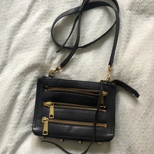 Rebecca Minkoff zipper bag - Rebecca Minkoff Zipper bag i mörklila. Några år gammal, lädret är i bra skick nitarna under har lite slitage, de bild.  Nypris 2000kr