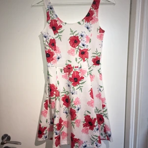 Söt blommig klänning från H&M - Klänning med röda och rosa blommor i strechigt material, från H&M. Sparsamt använd. 