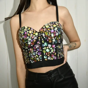 Strass Bustier - Säljer denna otroligt vackra och välgjorda bustier topp som är multifärgad.  Jag älskar denna topp och vill så gärna ha den kvar, men tyvärr så är den för stor kring bysten så kommer inte ha någon användning för den. Toppen har smala reglerbara axelband, tight passform samt lätt stretch. Toppen knäpps med ”hakar” baktill. Superfin till kjol, shorts, jeans eller läderbrallor! Köparen står för frakten. 