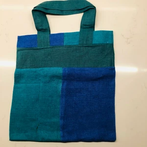 Tygkasse i återvunnet lin/ bomullstyg  - Tygkasse i overlock-sydda block i olika färger, i återvunnen textil. Handtagets höjd (från kassens kant) är ca 15,5 cm. Samfrakt är möjligt.