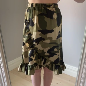 Kjol i mycket bra skick från grunt stl M (146-152 - Mycket fint skick och bra passform. Igensydd omlottkjol i militärmönster. Något glansigt tyg. 