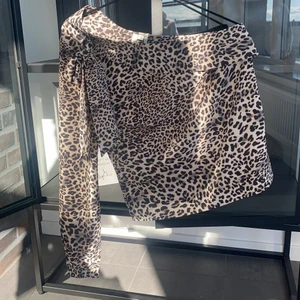 Oneshoulder blus i leopard med knytning vid axel  - Superfin oneshoulderblus i leopardmönster med knytning på axeln (se bild). Aldrig använd, lapp kvar. 