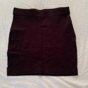 En svart kort kjol som sitter nära kroppen. Har använts en del men är i toppen skick