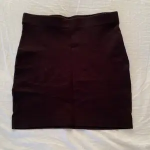 En svart kort kjol som sitter nära kroppen. Har använts en del men är i toppen skick