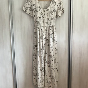 Blommig linneklänning  - Blommig maxiklänning från beyond retro. Aldrig använd. Har små axelvaddar. Ett av knapphålen är lite slitet. Storlek 34 men passar som 38