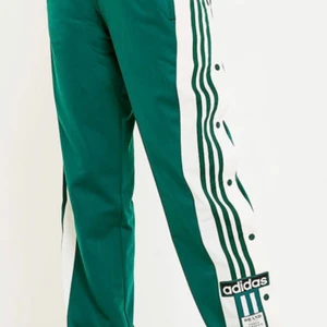 Adidas popper pants - Sjukt snygga och sköna svarta byxor från Adidas med gröna detaljer. Köpta för 800kr, men har blivit för små för mig. Pris kan diskuteras!