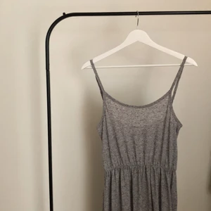 Grå långklänning  - Grå långklänning med detalj vid midjehöjd.