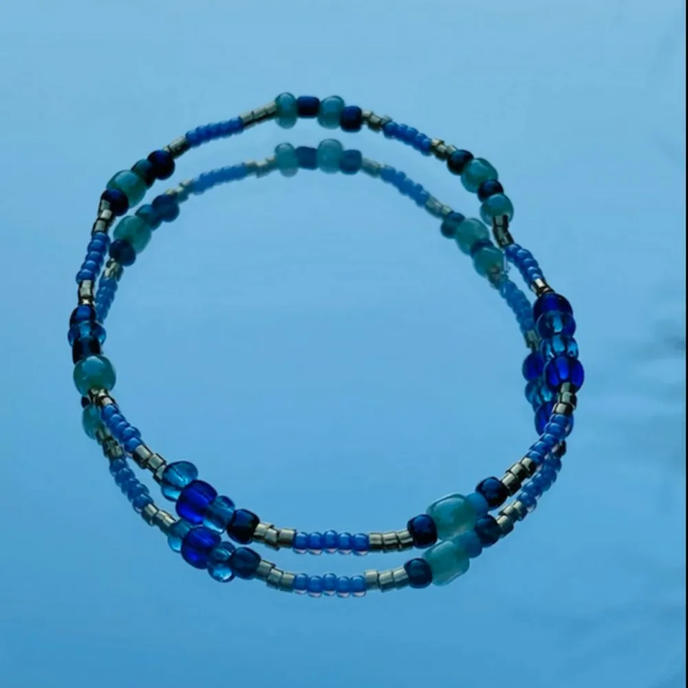 Egengjort armband med elastiskt band i fina blåa färger. 🌊💙. Accessoarer.
