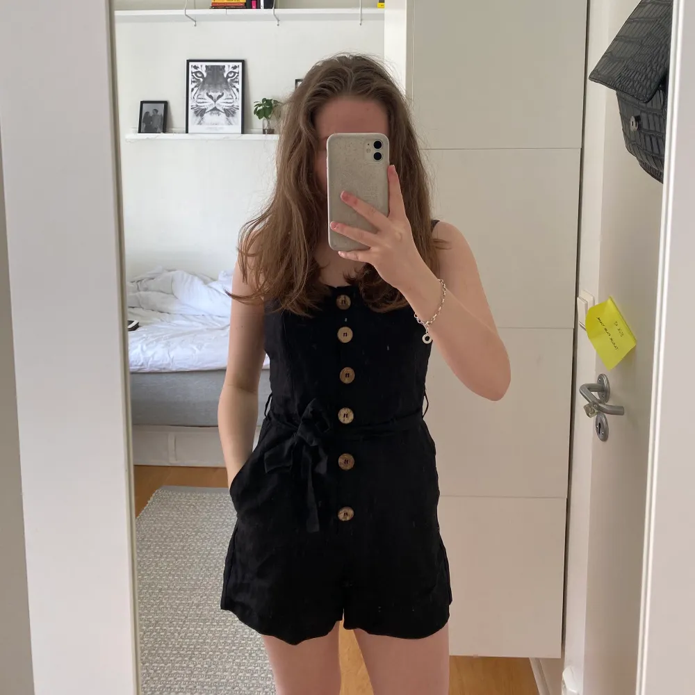 En jättesnygg svart playsuit från mango (52% linne och 48% vicos) i storlek S. Den har breda axelband, den har fickor, knappar som man knäpper fram och ett band i midjan som man kan knyta hur man vill eller ta bort. Den har bara använts 1-2 gånger och är därför i nyskick. Säljer den för 100kr + 66kr spårbar frakt och köpte den för runt 300kr. Klänningar.