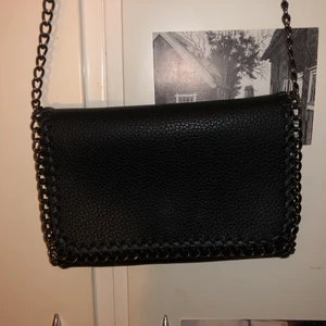 Svart väska i fake läder - Svart läderväska med mörka kedje detaljer. Använd ca 2 gånger. Köpare står för frakt💕