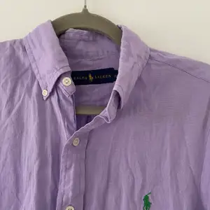 Ralph Lauren skjorta lila i 100% linne. Jättefin och perfekt med linne nu till sommaren. I superbra skick då den var lite för liten för min man (knapp använd). Storlek small.