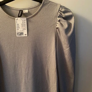 Ribbad klänning från HM - Jag säljer denna  klänningen från H&M, den är aldrig använd och jag hoppas därför att det finns någon annan som kan få den att komma till användning! Den är silvrig i färgen och går lite under knäna. 