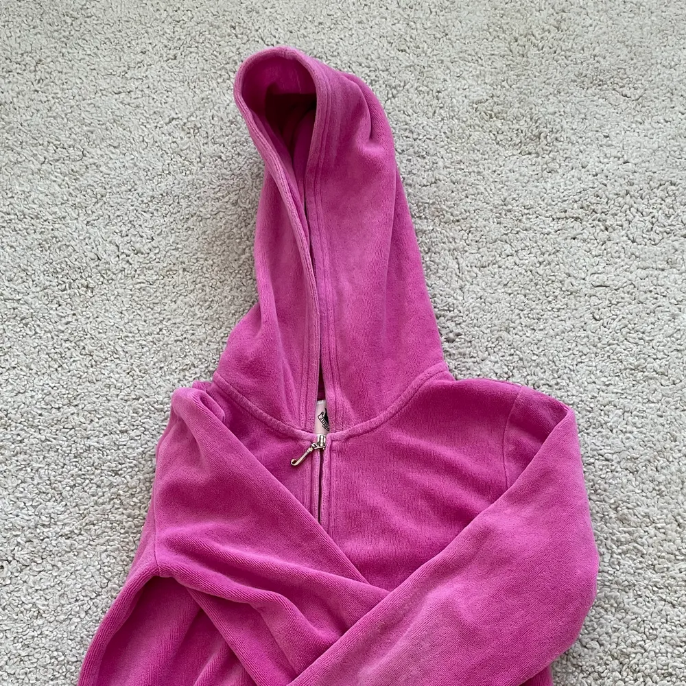En sjuktsnygg Juicy Couture tröja. Den är rosa och coola detaljer på baksidan. Koftan har en dragkedja som fungerar och har en luva. Tecken på användning finns men lätt att fixa.Står att de är storlek L men skulle säga att den är en XS. Tröjan är croped.                                       ❗️KÖPAREN STÅR FÖR FRAKT❗️. Hoodies.