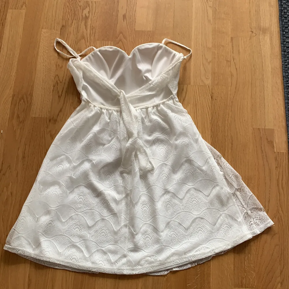 En vit kort klänning med mönster som knyter i ryggen från nelly. Den är i storlek 34 men har resår så passar många kroppstyper. Använd 2 gånger.. Klänningar.