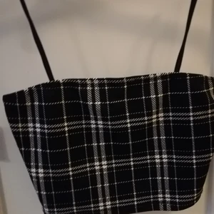 Shien storlek xs  - En svart rutig magtopp. Aldrig använd är i bra skick. Axel banden är inte reglerbara. Köparen står för frakten. Frakten ligger max på 48kr det kan sänkas. 