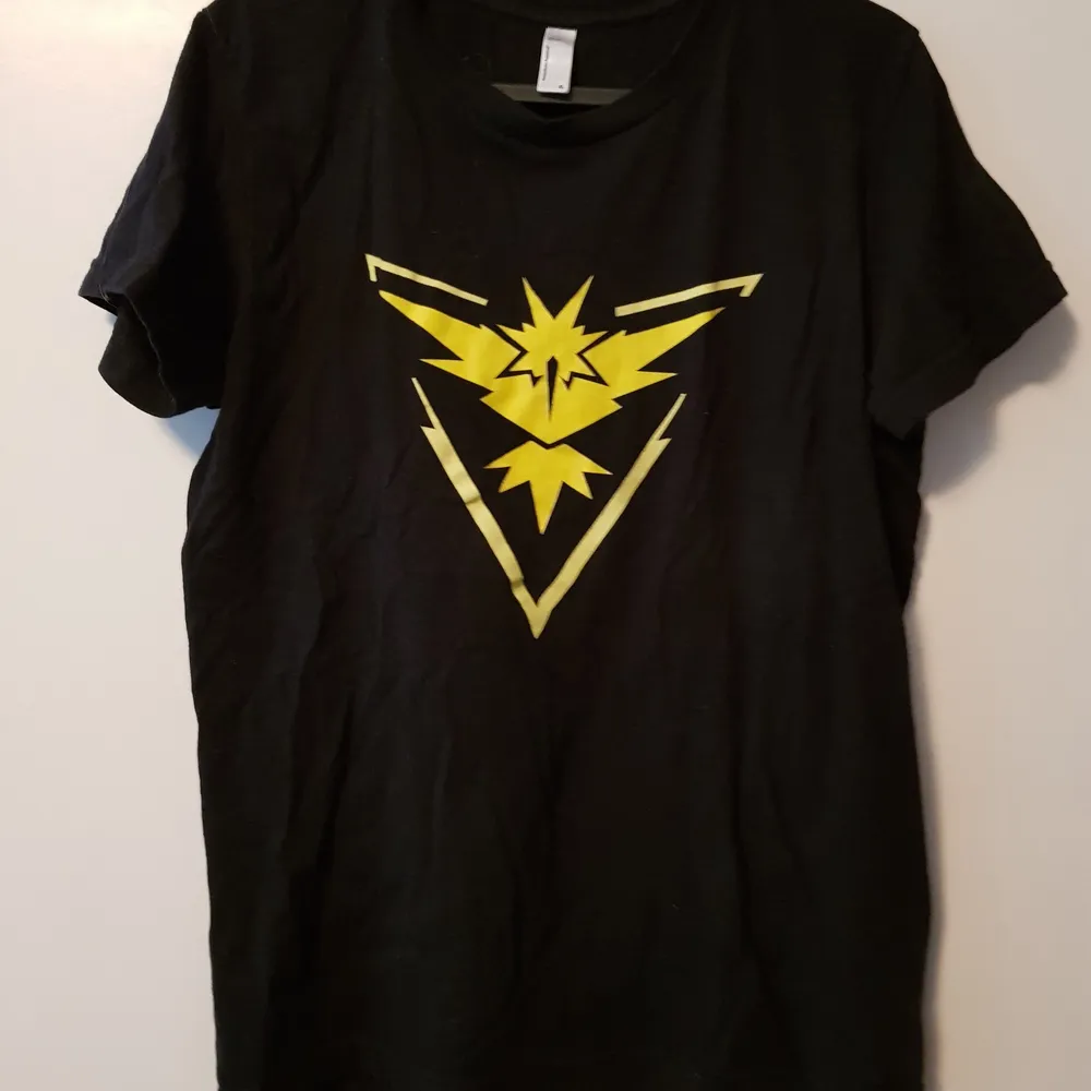Liten i storleken, skulle säga S/M istället för XL. Team Instinct symbolen från Pokemon GO. Inga fel. Kan ha päls på sig (har katter). . T-paidat.
