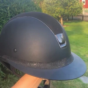 SAMSHIELD HJÄLM TILLSALU!  - Super fin Samshield hjälm tillsalu! Nypris: 7200:- mitt pris 2900:-! Priset kan sänkas vid snabb affär. Fint skick och hjälmen har aldrig varit i backen. Stl: 58 med solskärm. Egendesignad med mocka uppe på och glitter runt om! 💗
